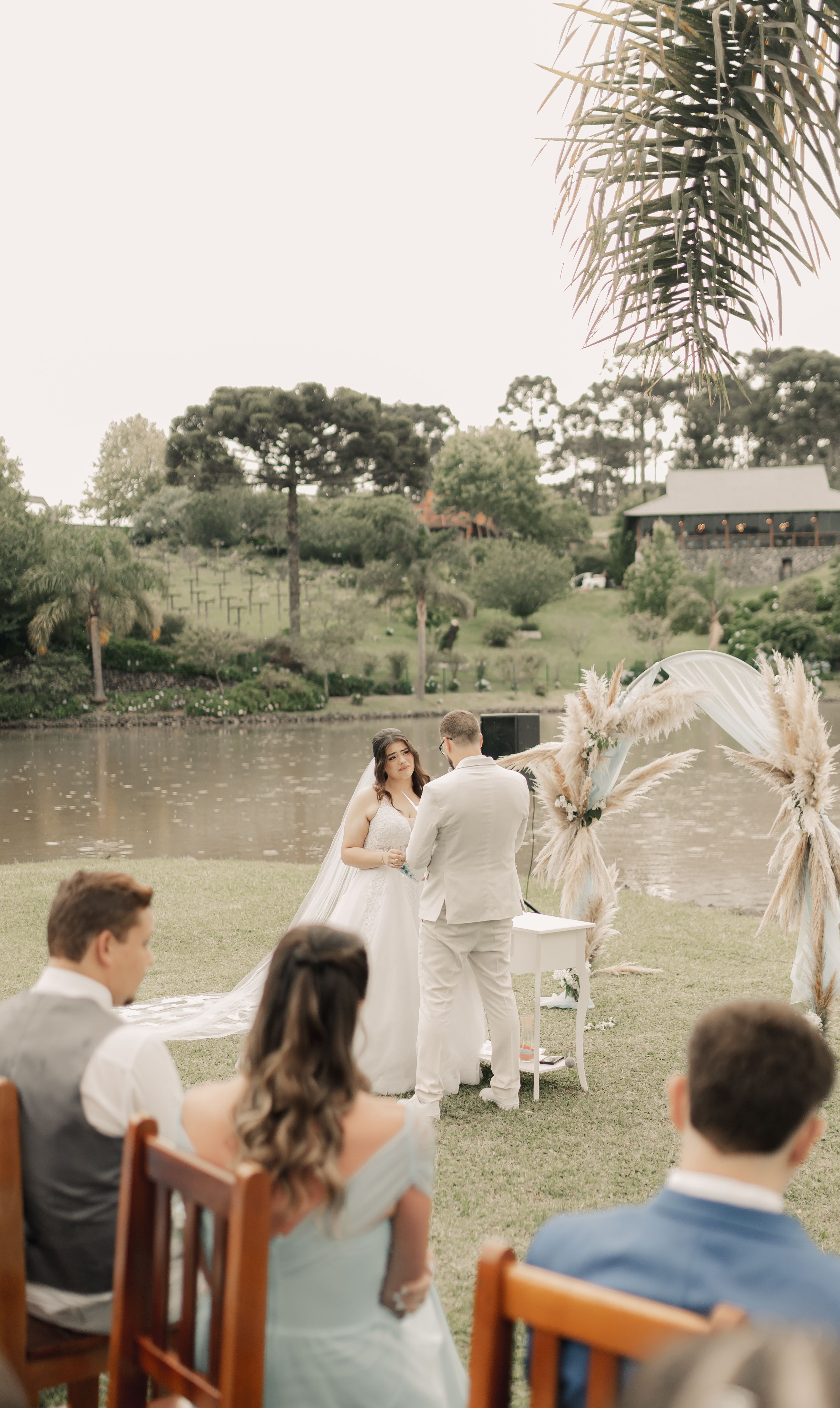 A serene outdoor wedding by a lake, capturing a bride and groom exchanging vows.