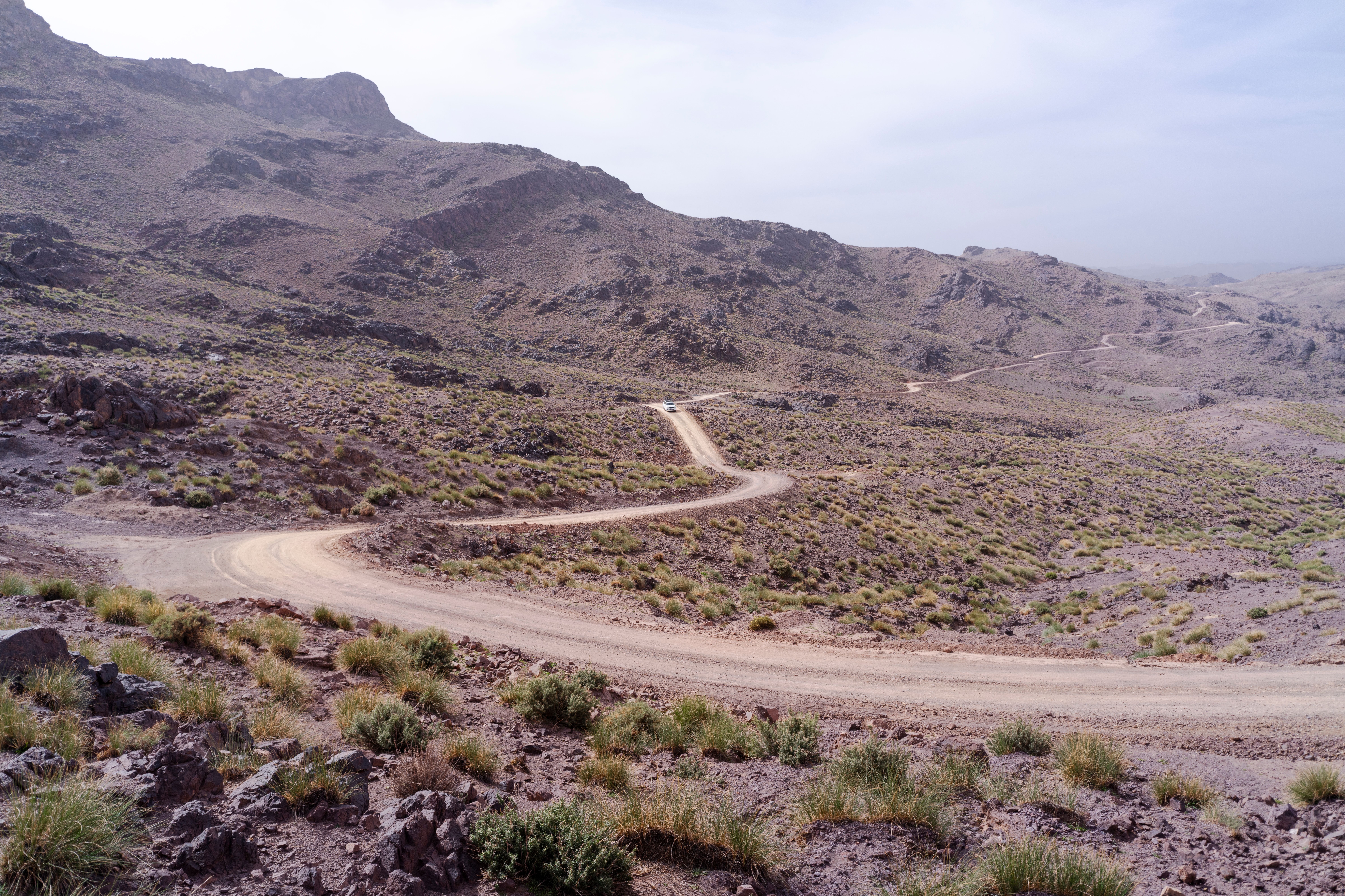Dirt road winding through the rugged and arid Moroccan desert landscape.