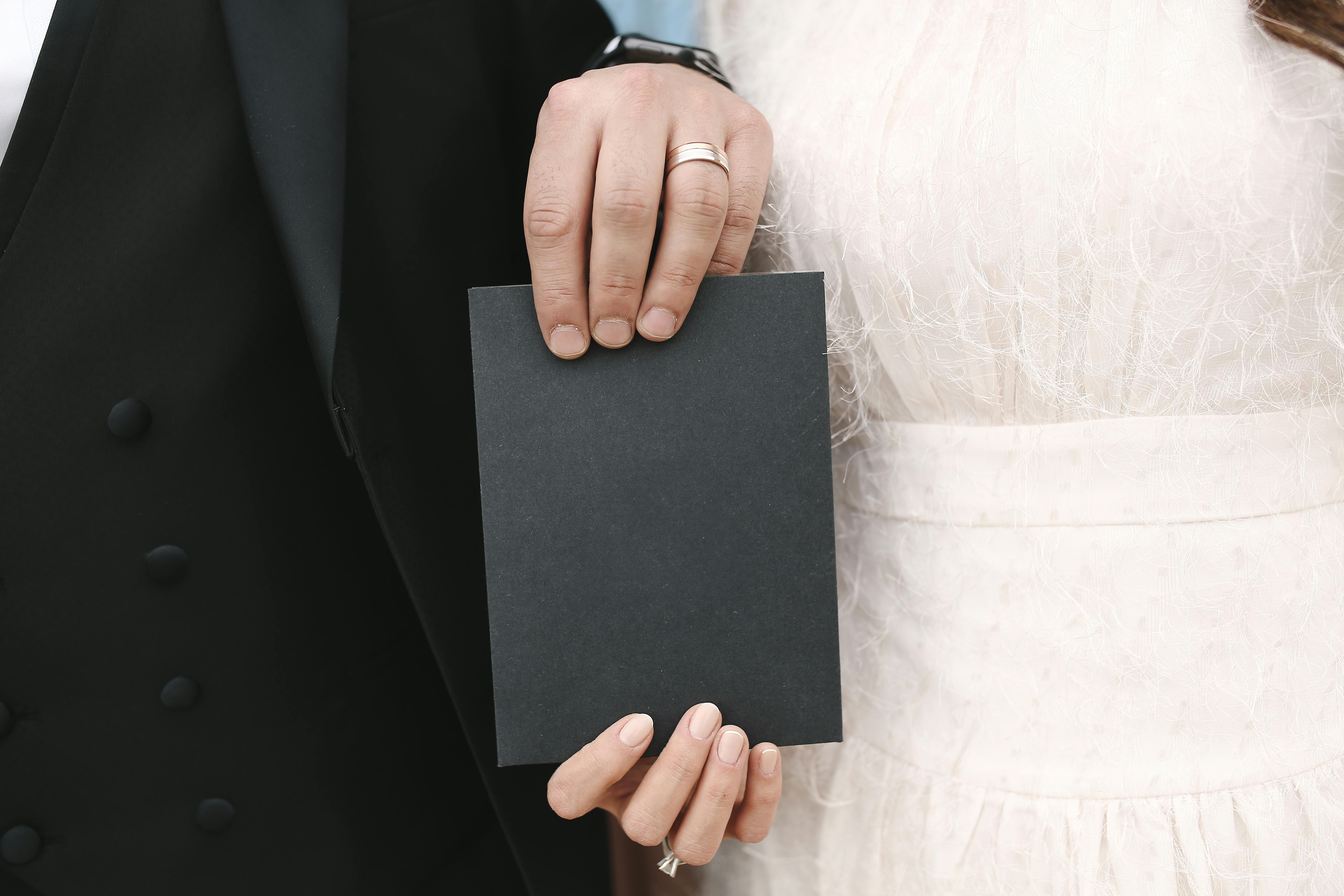 Wedding couple holding a blank card, showcasing their elegant attire.