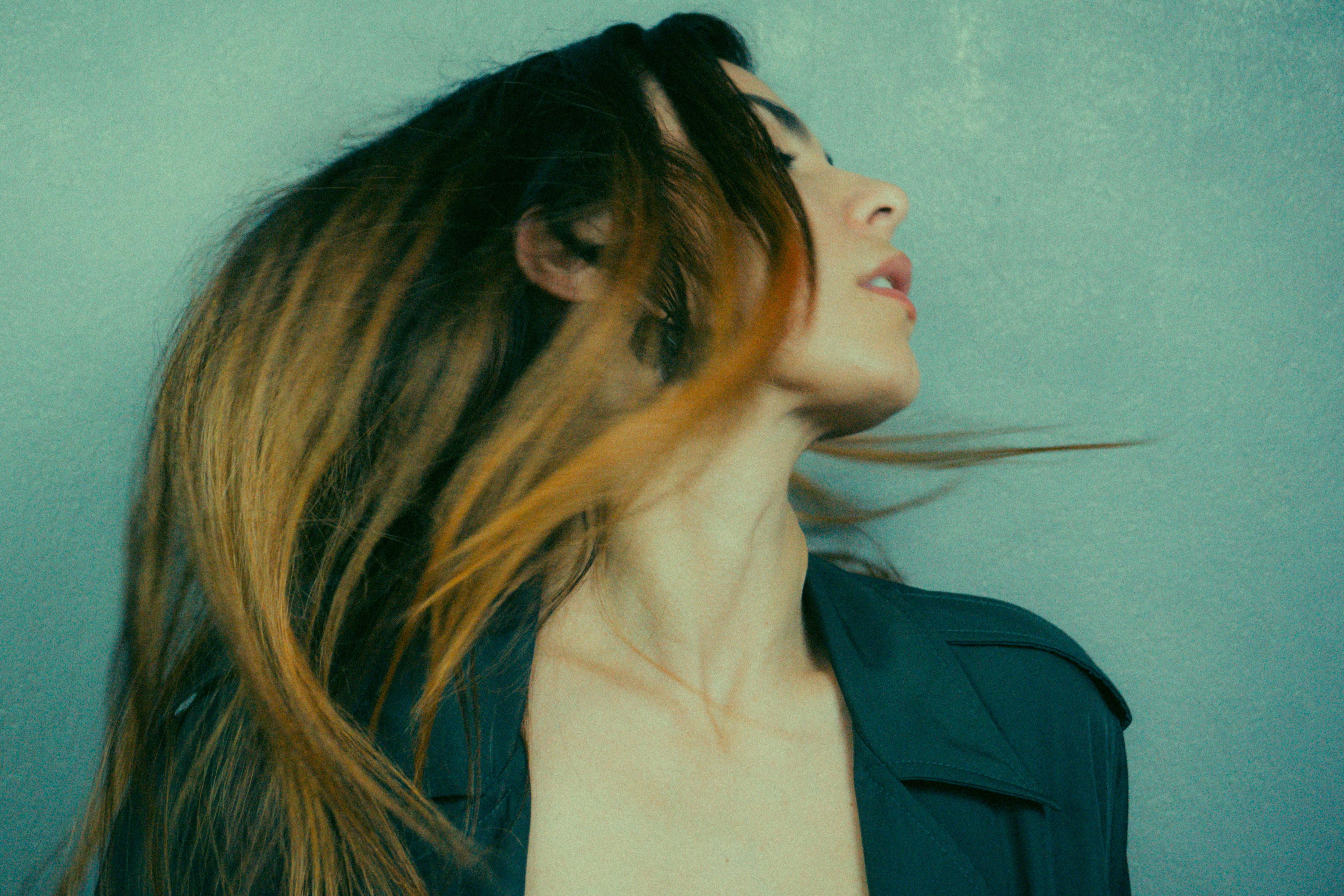 Artistic portrait of a woman in motion with flowing hair set against a muted background.