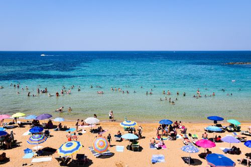 Free Crowded beach day with colorful umbrellas and swimmers in Apulia, Italy. Stock Photo