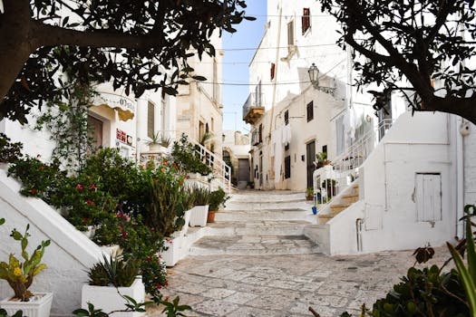 Explore the picturesque whitewashed streets of Ostuni in Apulia, Italy, with lush greenery.