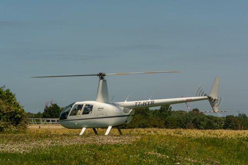 Free White helicopter standing on a grassy field on a sunny day with clear skies. Stock Photo