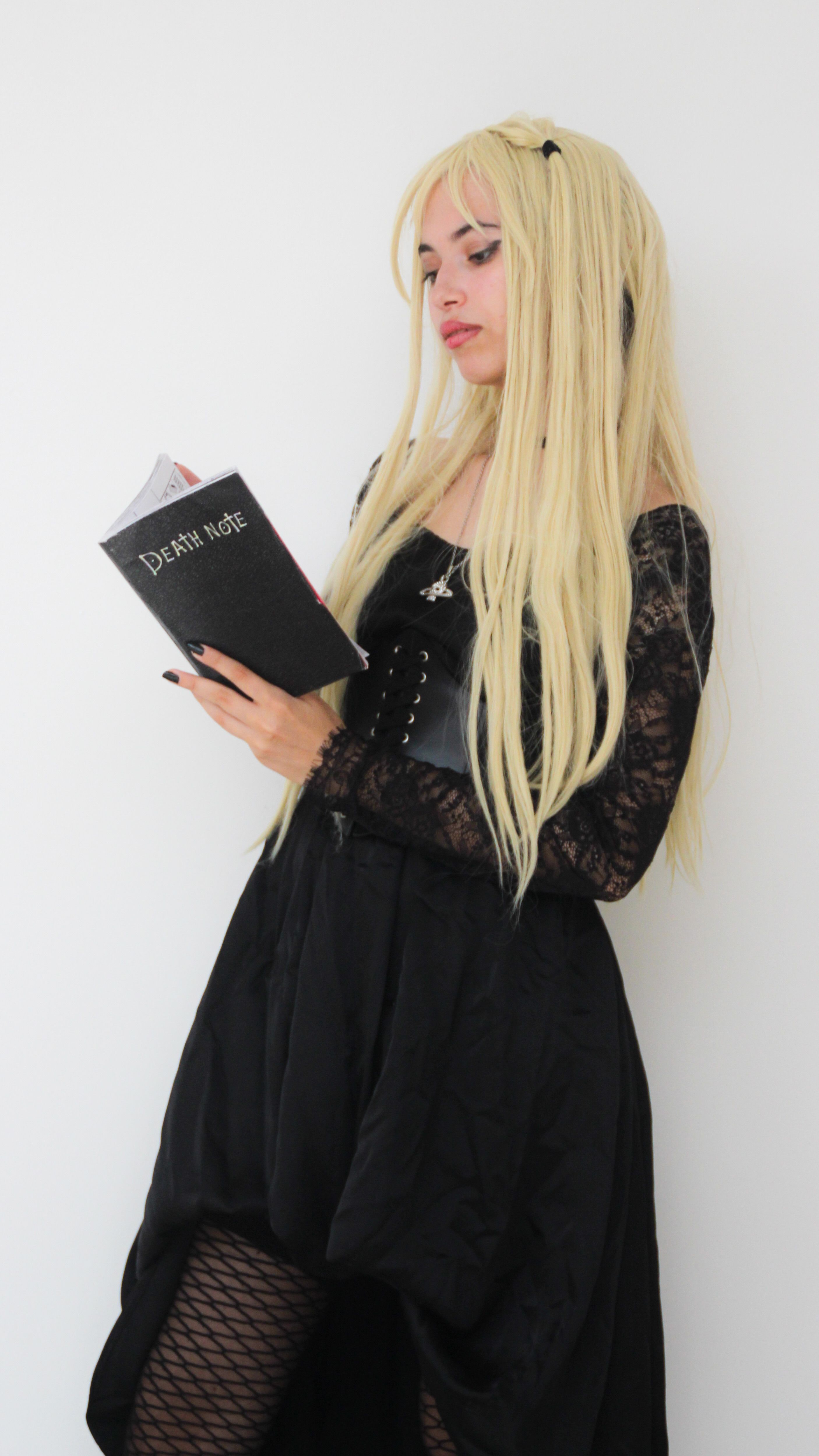 An adult in anime-inspired cosplay holding a themed book, reflecting the costume contest and cosplay panel at the library convention
