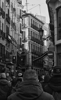 Black and white street view of Madrid's historic architecture bustling with people.
