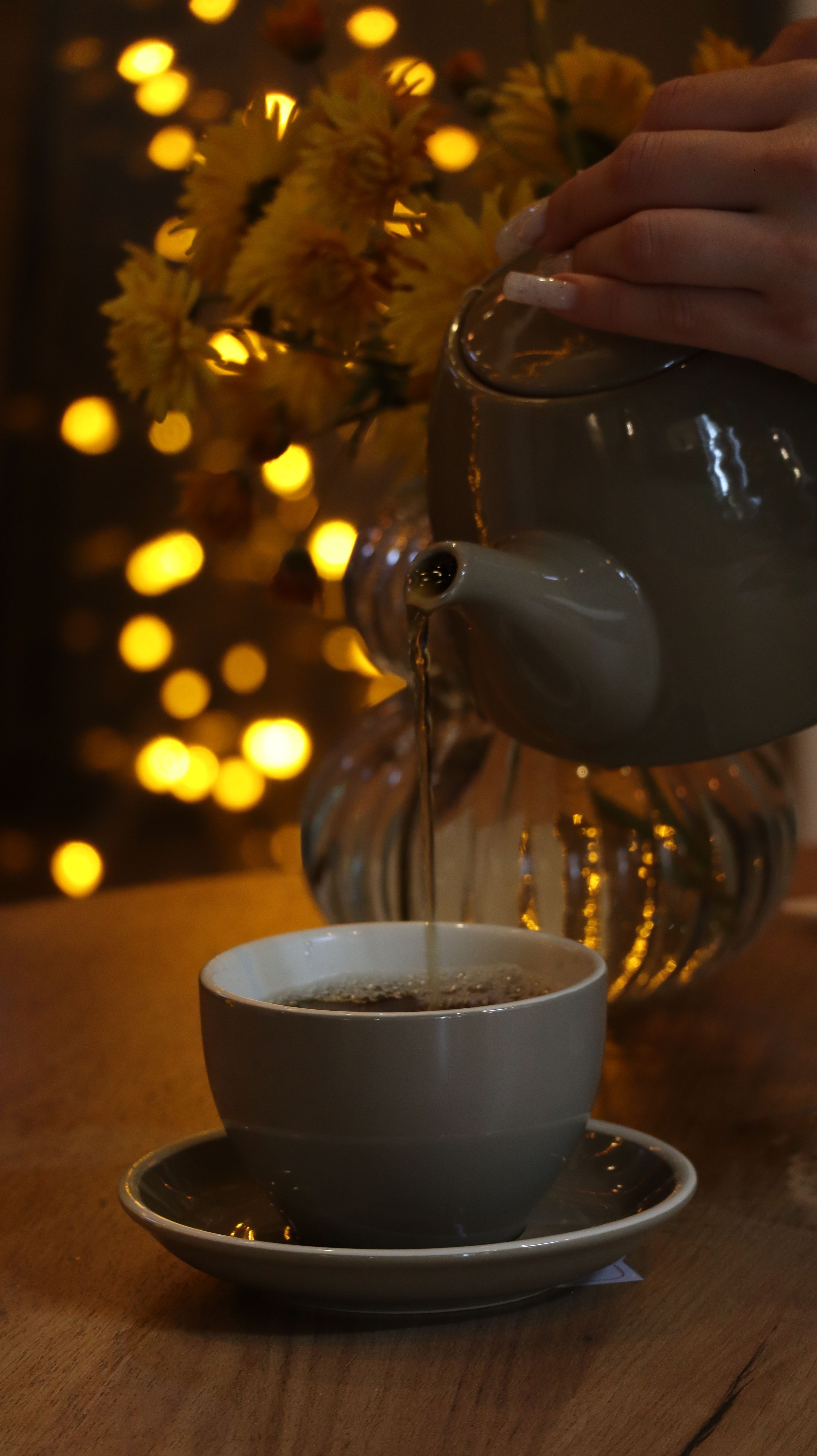 Delightful tea being poured amidst warm yellow bokeh lights creating a cozy atmosphere.