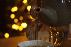 Delightful tea being poured amidst warm yellow bokeh lights creating a cozy atmosphere.