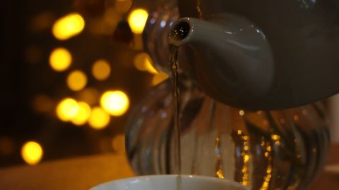 Delightful tea being poured amidst warm yellow bokeh lights creating a cozy atmosphere.