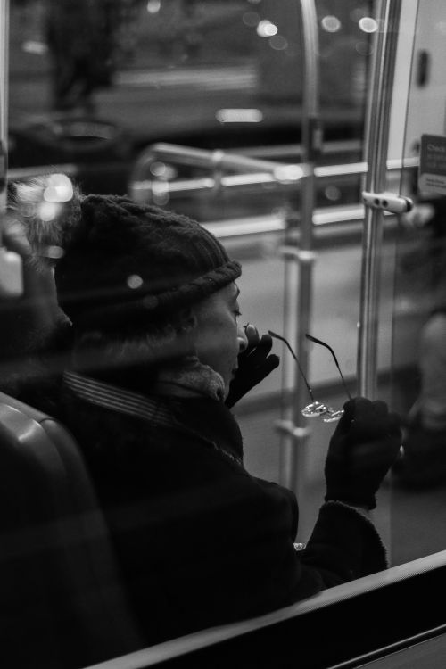 Free A contemplative woman in winter attire on a bus adjusting her glasses. Stock Photo