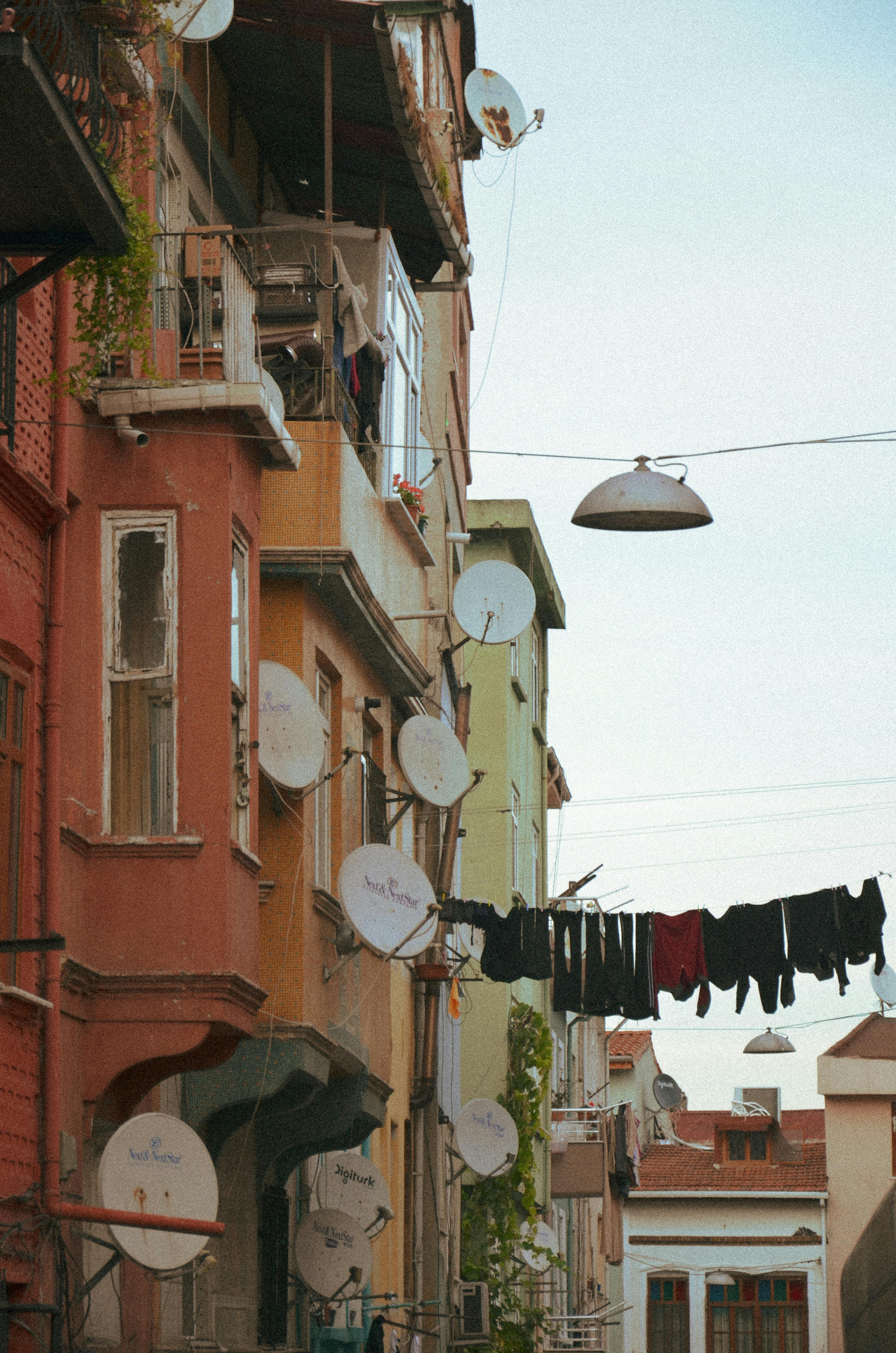 Colorful urban street with satellite dishes and laundry on balconies.