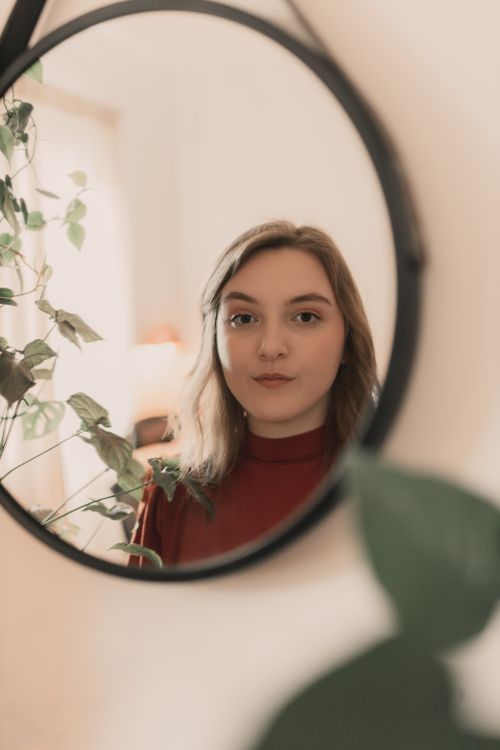 Free Young woman reflected in a mirror surrounded by indoor plants. Stock Photo
