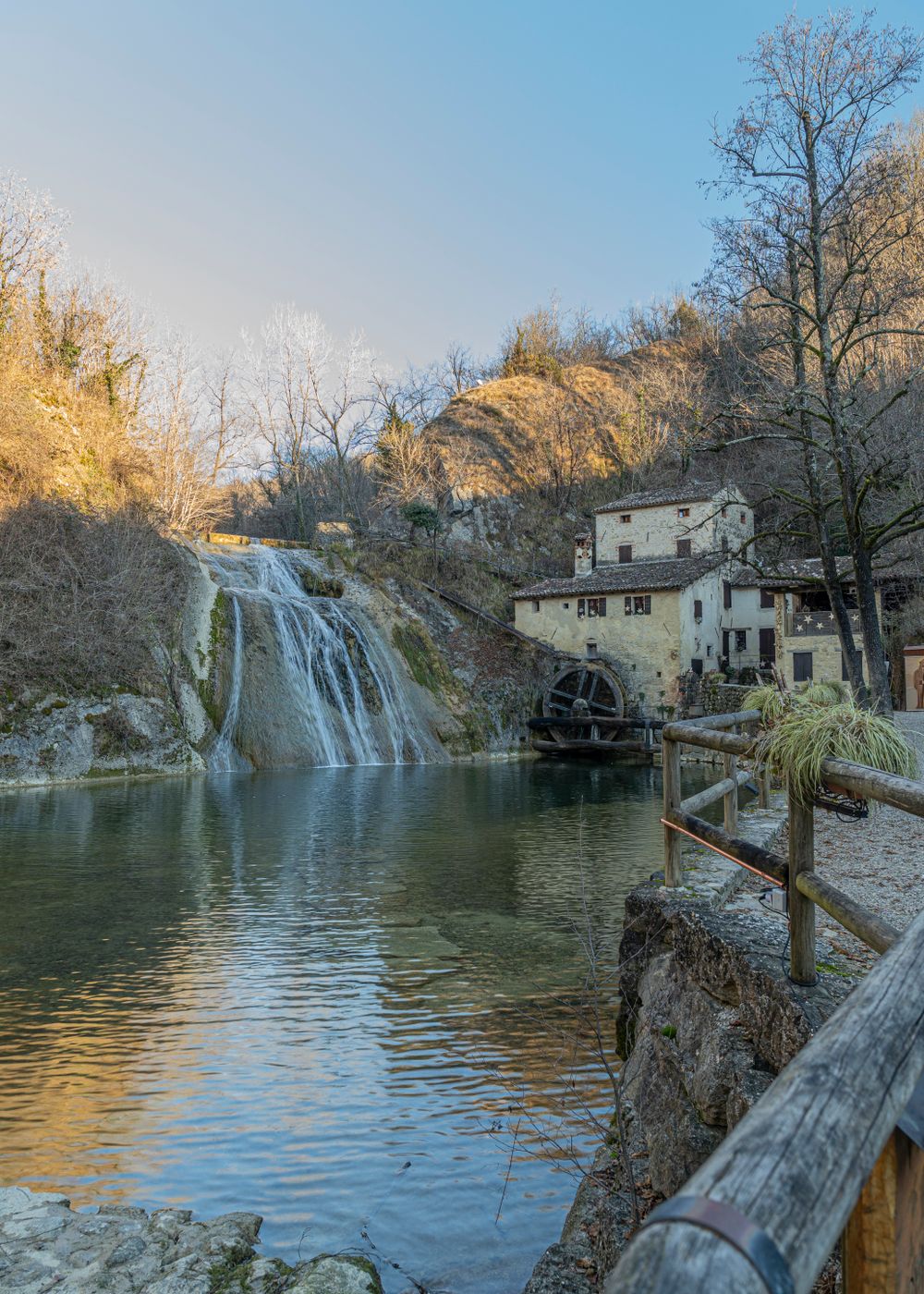 Cascadă termală lângă o moară veche de piatră, cu bazine naturale de calcar