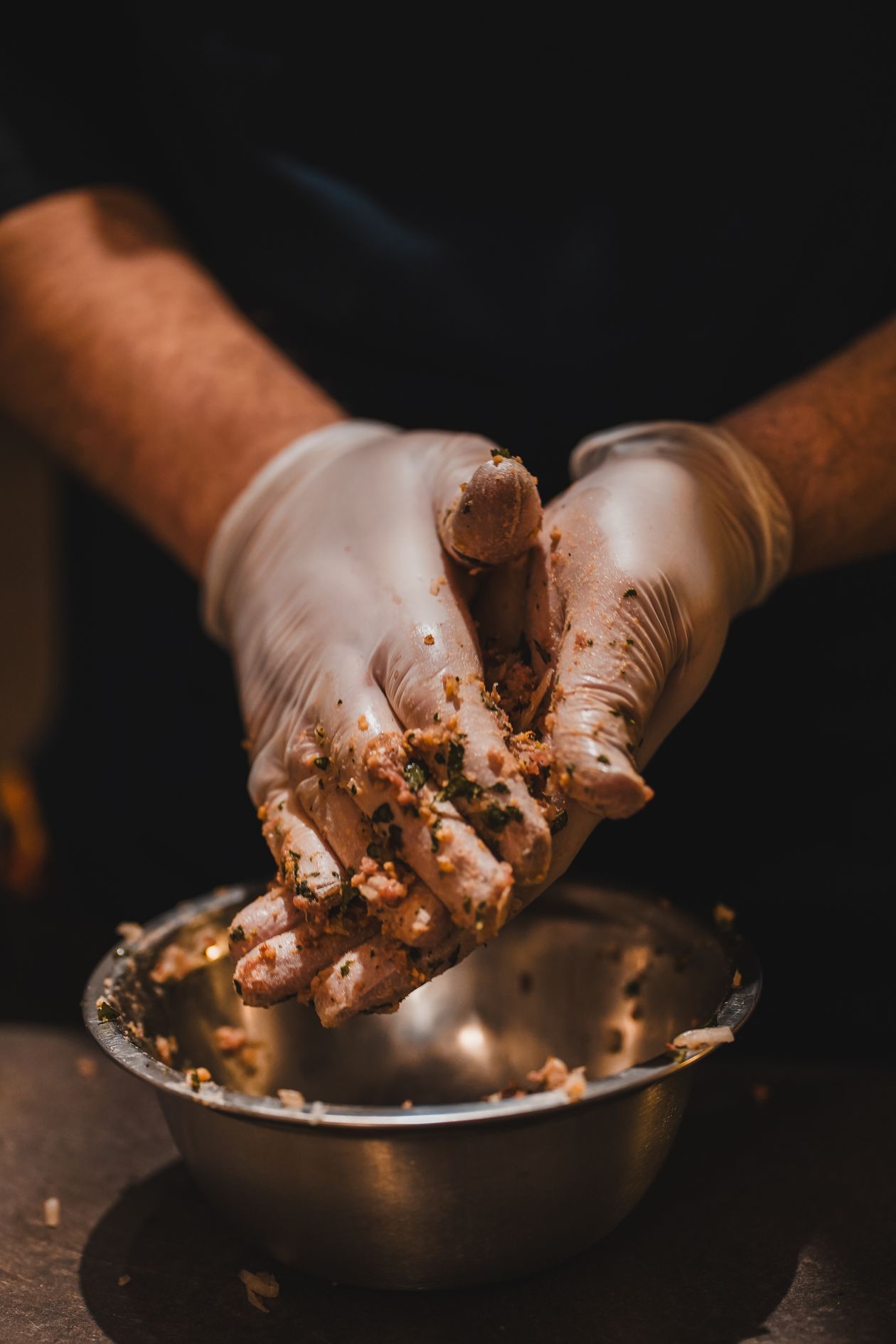 Chef shaping chicken meatballs by hand with gloves for hygiene