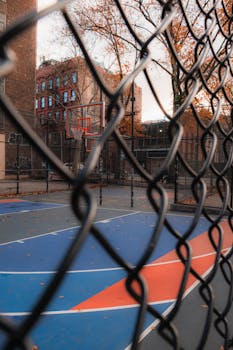 Outdoor basketball court with vibrant autumn leaves and a city backdrop.