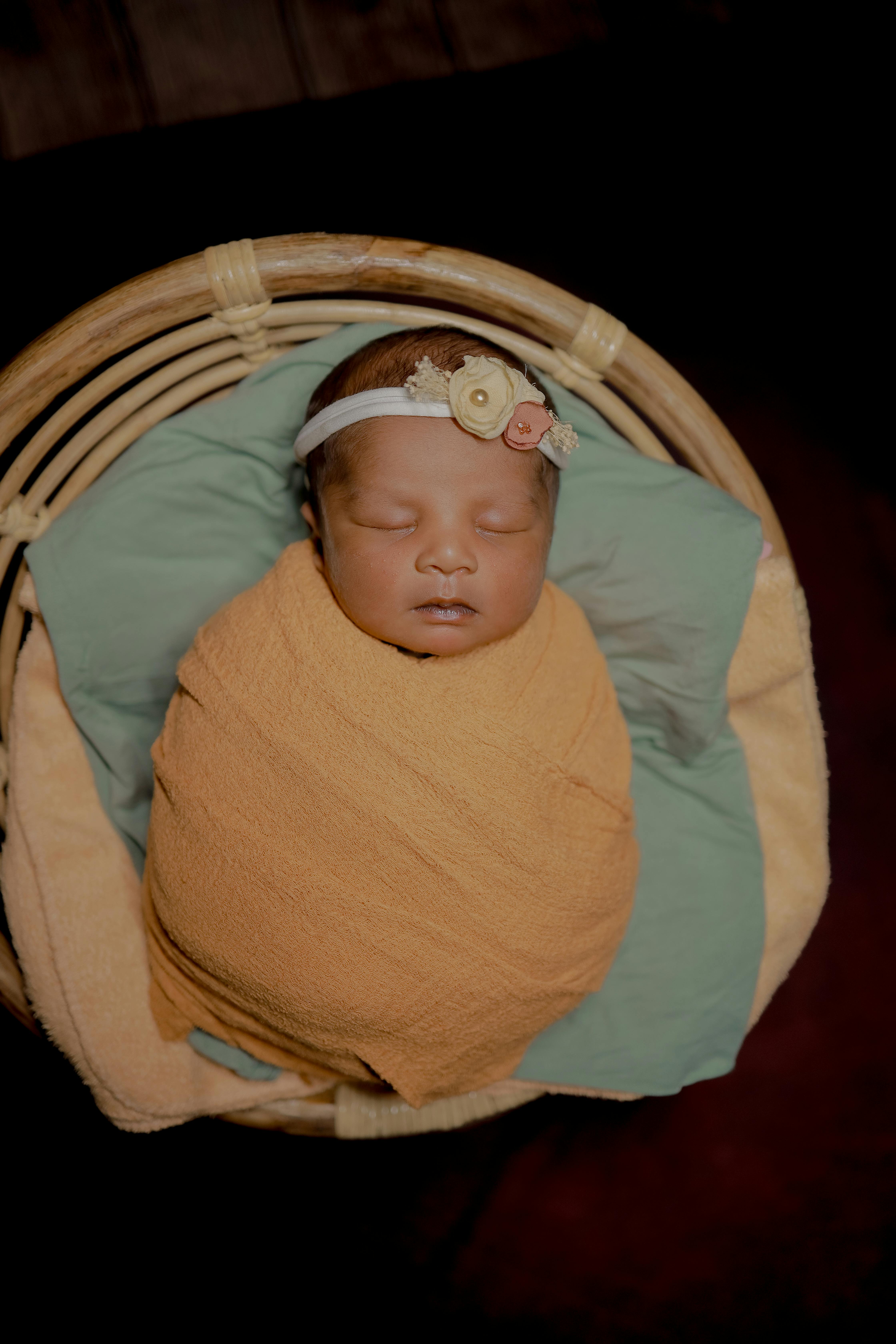 A serene image of a newborn baby peacefully asleep in a beautifully wrapped basket.