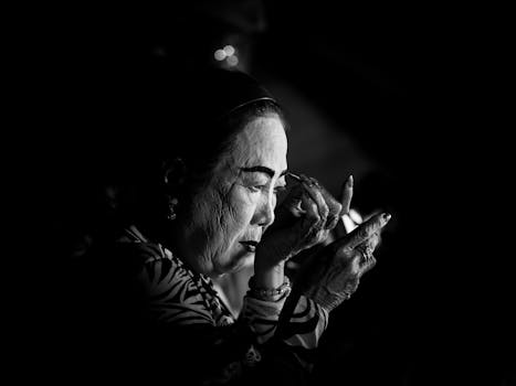 Black and white portrait of an elderly woman putting on makeup, showcasing fine details and expressions.