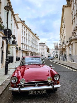 Vintage red car parked on a picturesque street in London, showcasing classic architecture.