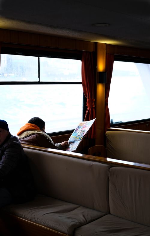 Free A man reading a newspaper on a cozy ferry in Istanbul, enjoying a tranquil travel experience. Stock Photo