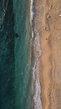 A breathtaking aerial view of a remote sandy beach meeting clear ocean waters.