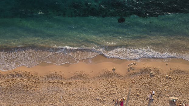 Drone shot capturing a picturesque sandy beach with gentle ocean waves.