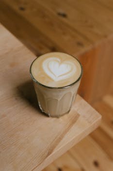 Latte with heart-shaped foam art on a wooden table in Sabinov, Slovakia.