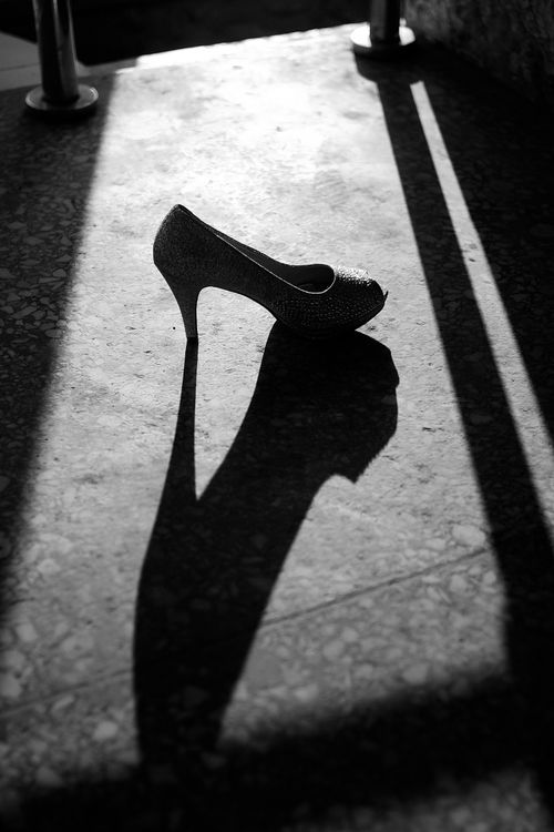 Free A high heel shoe casting a striking shadow on a textured floor in Jos, Nigeria. Stock Photo
