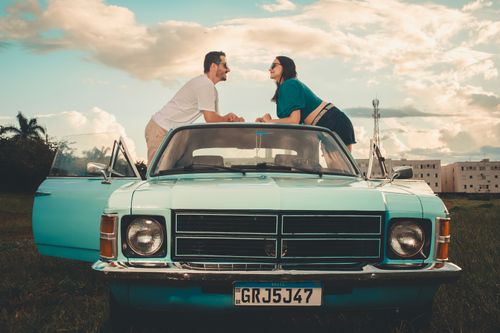 Free A young couple enjoying a sunny day on a classic convertible in an open field. Stock Photo