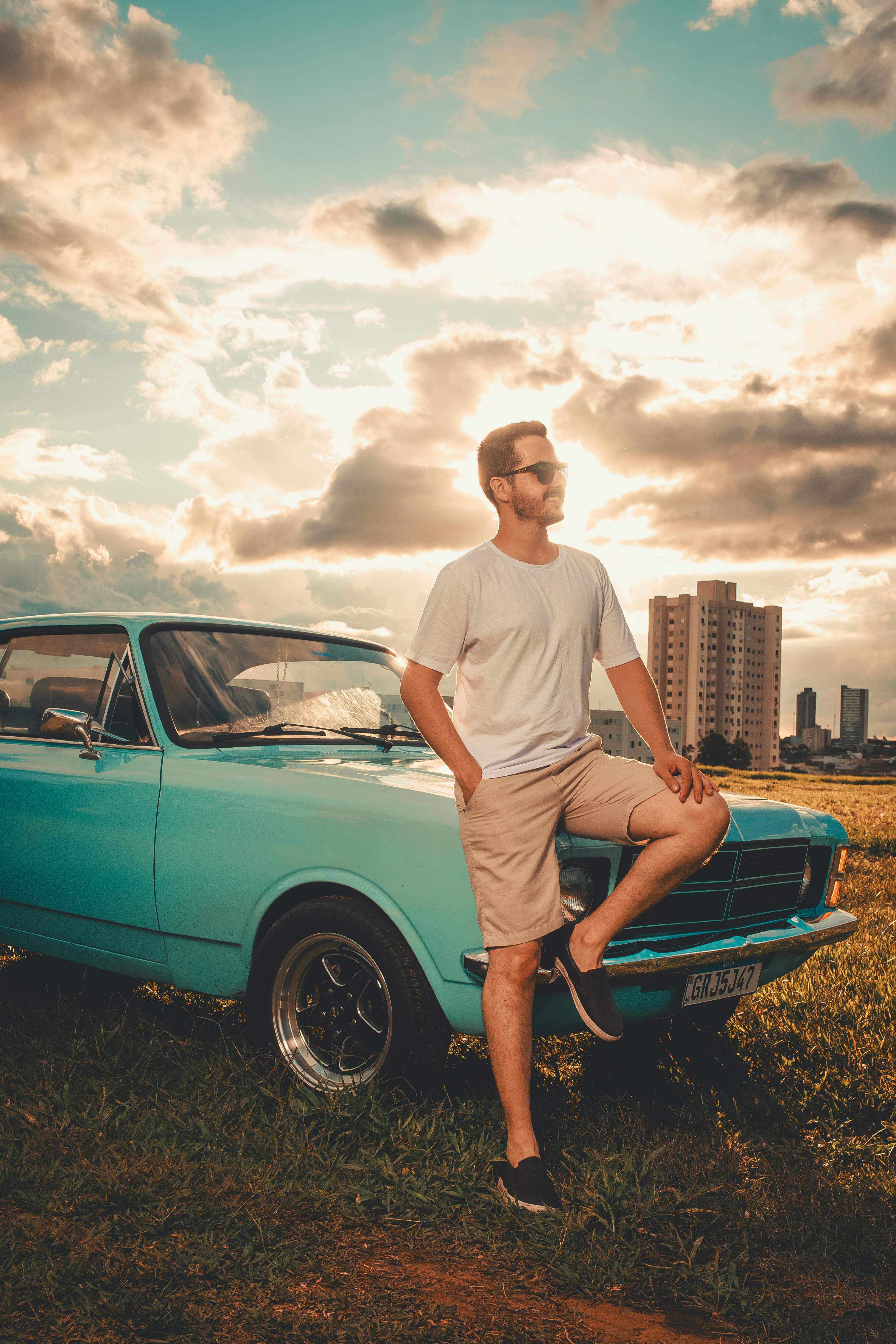 man posing with vintage car at sunset