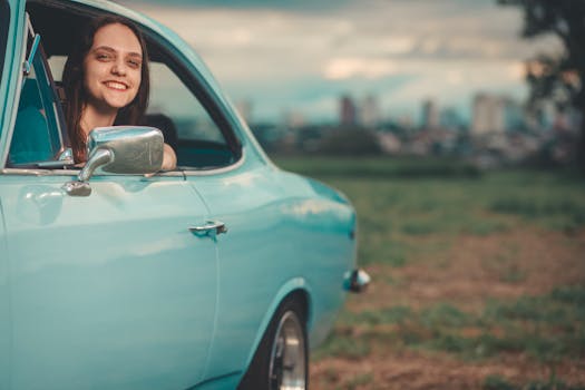 A young woman smiling from a vintage car window with an urban skyline in the background.