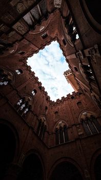 Dramatic view of a historic Italian courtyard looking up to the sky with intricate architecture.