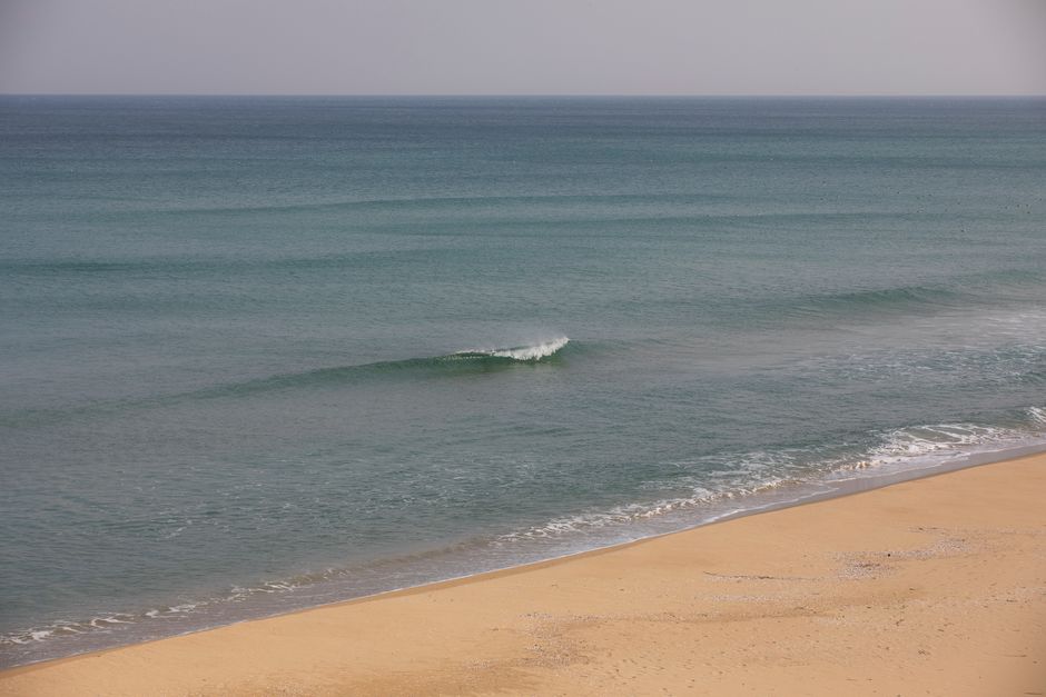Calm ocean waves on a deserted sandy beach during daylight.