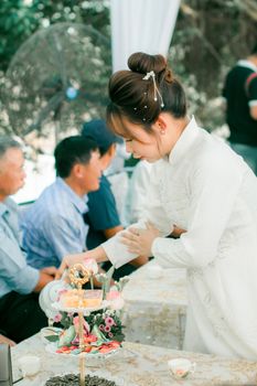 Woman in traditional dress pouring tea during cultural ceremony outdoors.