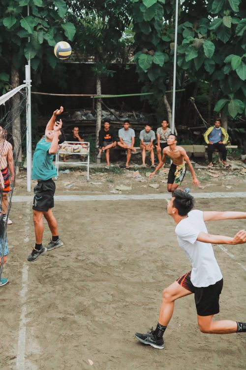 Free Energetic outdoor volleyball match on a rustic dirt court with players in action. Stock Photo
