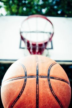Vivid image of a basketball aiming for a hoop outdoors in daylight.