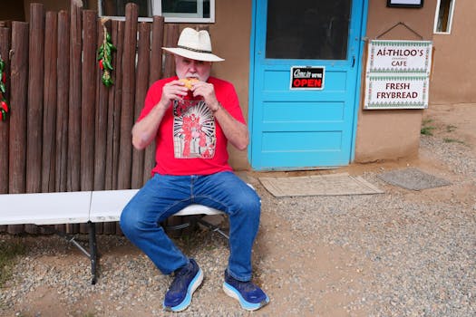 Man seated by Ai-thloo's Cafe eating fresh frybread at Taos Pueblo.