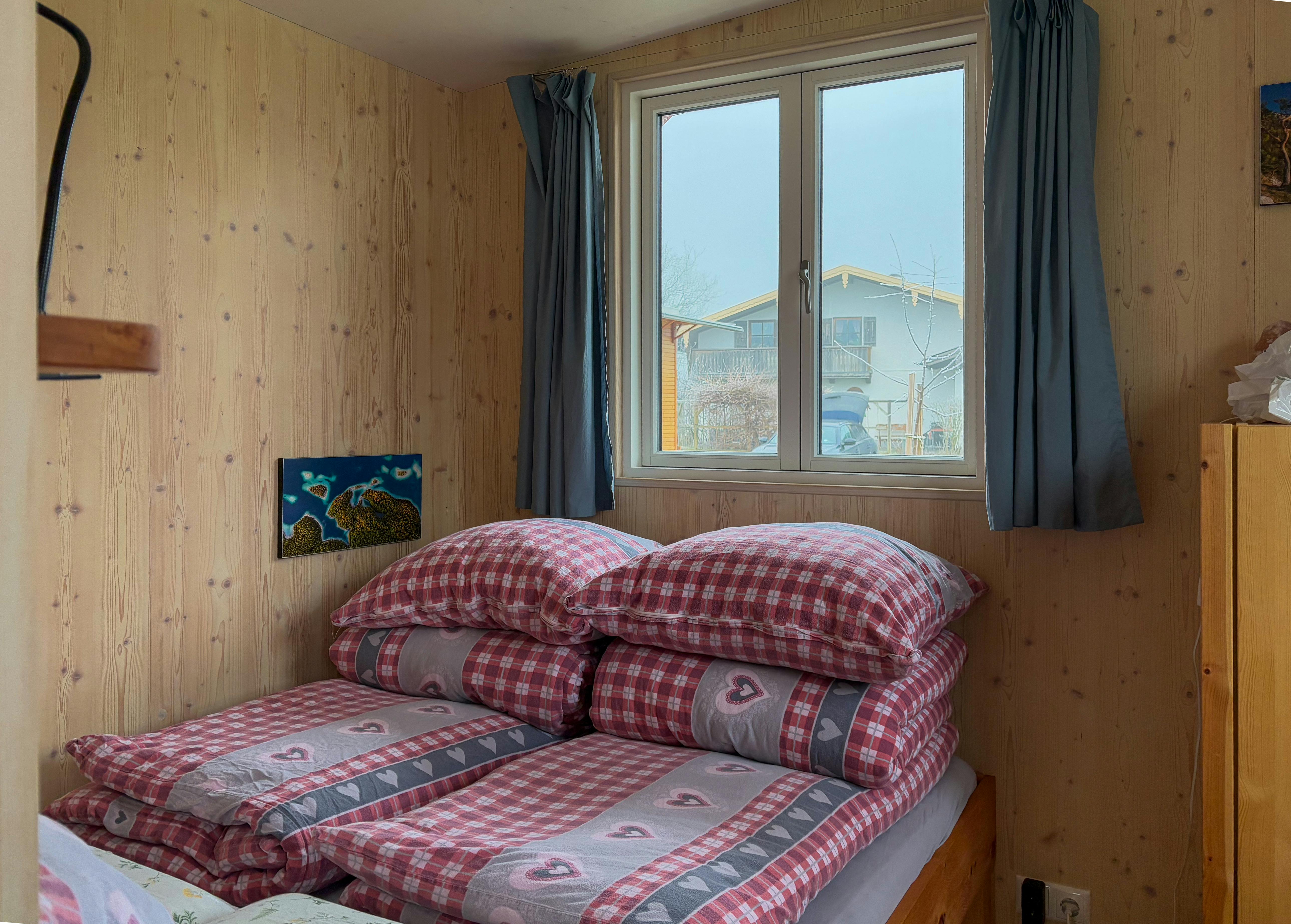 Comfortable bedroom in a wooden cabin featuring plaid bedding and a window view.