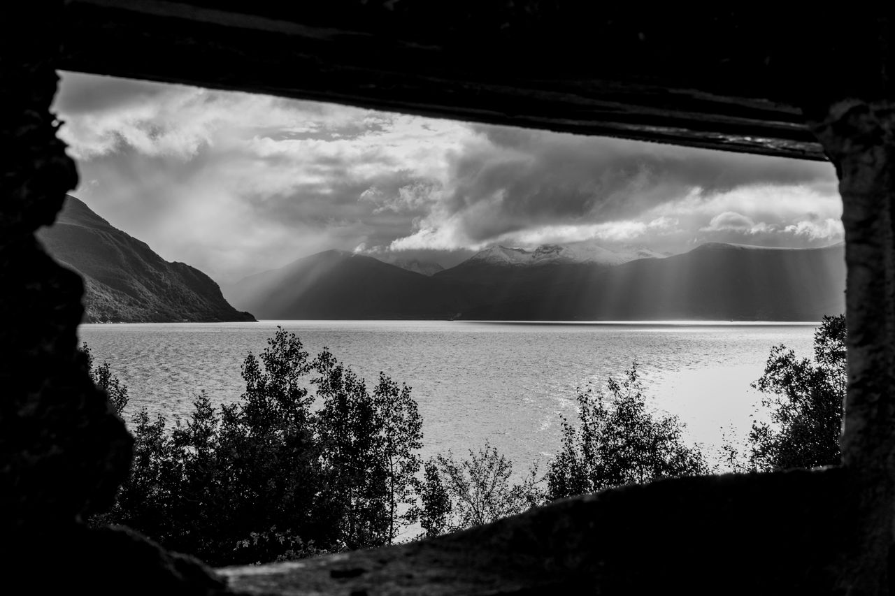 dramatic black and white shot of a lake framed by mountains and clouds