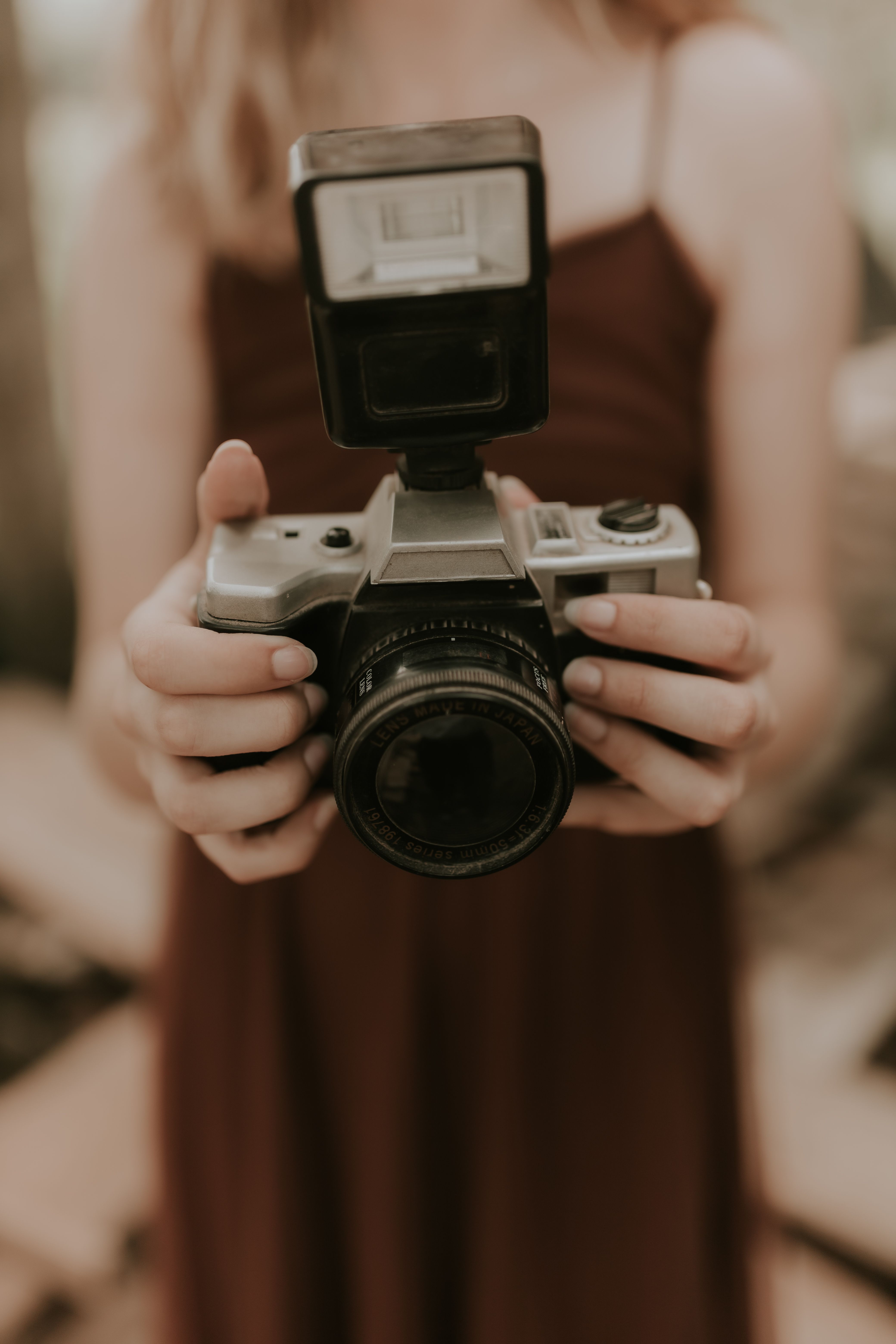 Close-up of a young woman holding a vintage camera with flash.