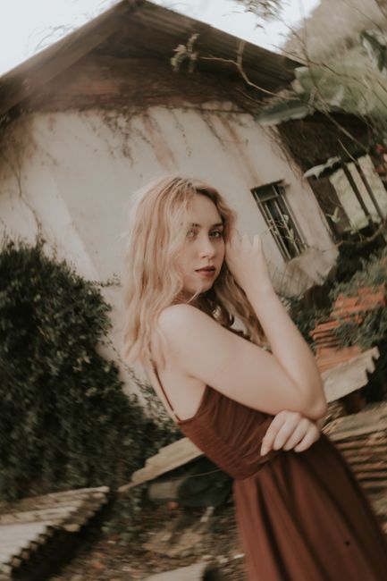 Artistic portrait of a woman with vintage style in an outdoor setting.