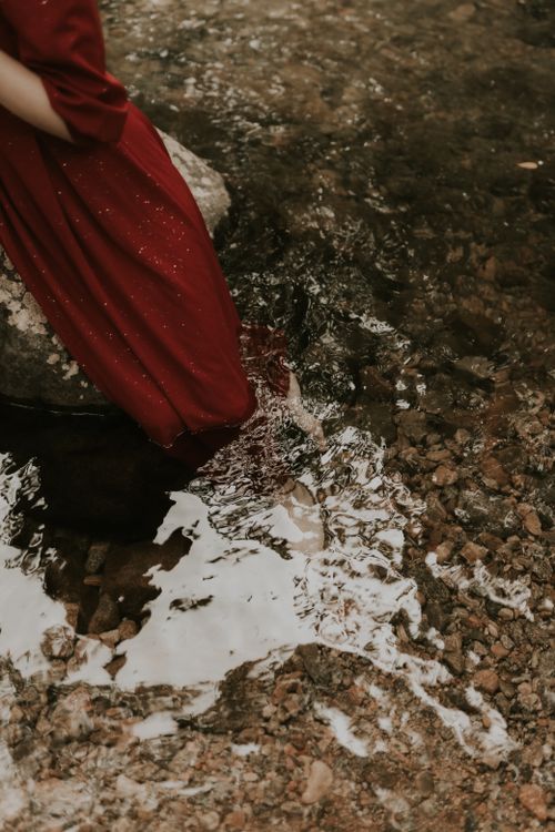 Elegant Woman in Red Dress by Flowing Stream · Free Stock Photo