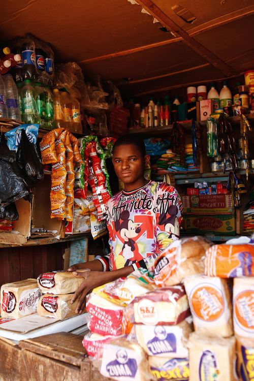 Free Young shopkeeper in a colorful Abuja market stall selling diverse groceries. Stock Photo