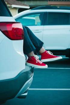 一双红色运动鞋从停放的汽车里伸出来，增添了休闲时尚和旅行氛围