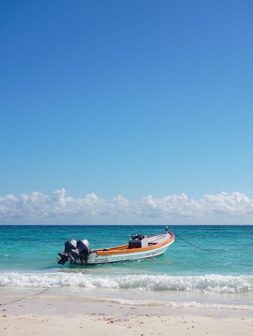 Free A peaceful scene of a boat moored on Playa del Carmen's beach under a clear blue sky. Stock Photo