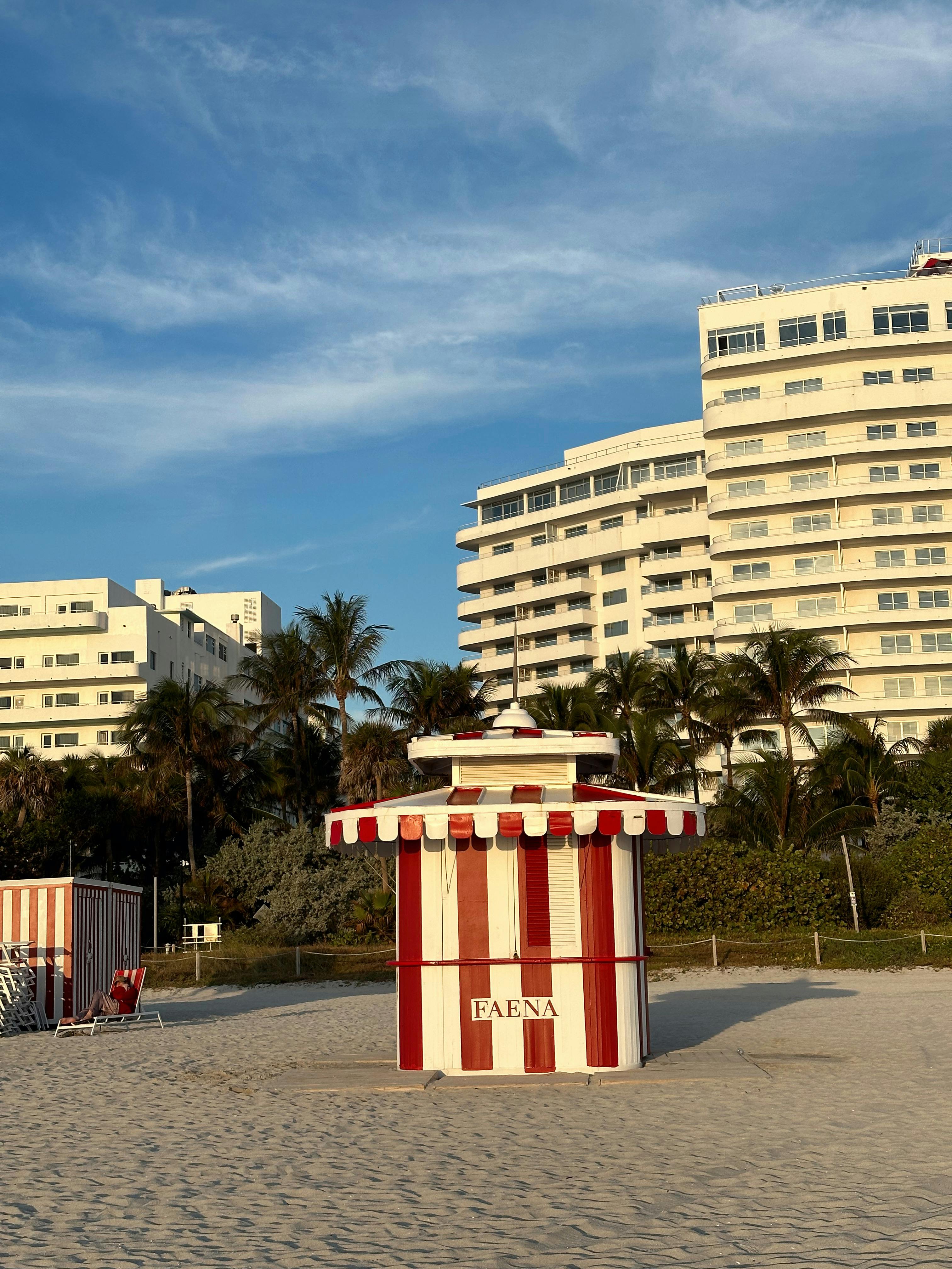 A red and white beach cabana with the Miami skyline in the background.