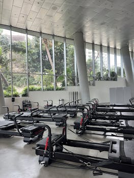 Spacious gym with sleek rowing machines and large windows offering a lush outdoor view.