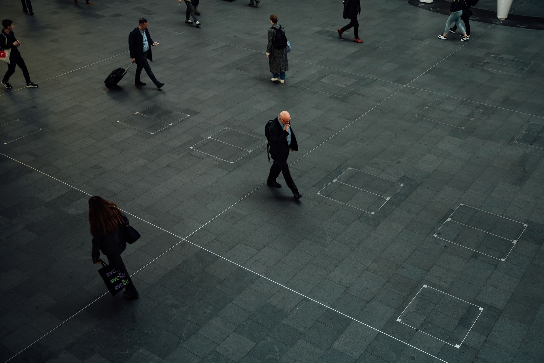 Busy commuters walking in a modern outdoor plaza in London, England.