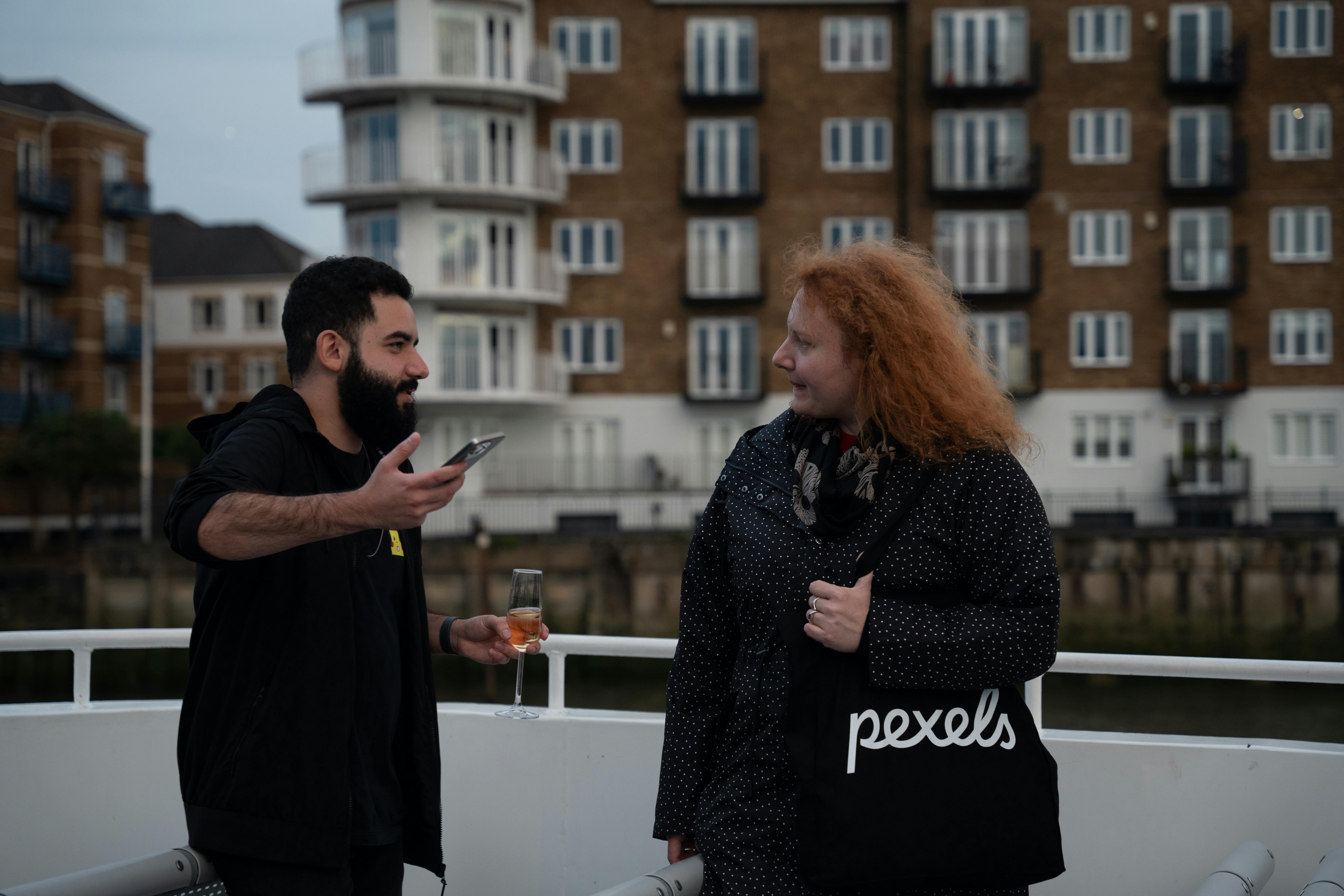 Two people talking and enjoying a drink on a boat in London, UK.