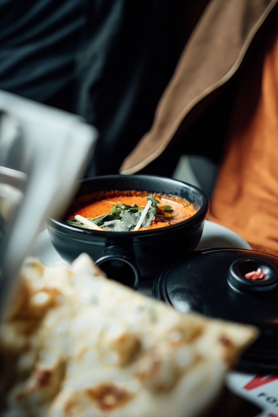 Indian curry with herbs in a black bowl