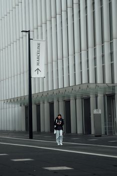 Person walking by a contemporary building facade with vertical lines in London.