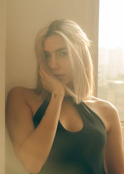 Artistic portrait of a woman with blonde hair and tattoos in warm sunset light.